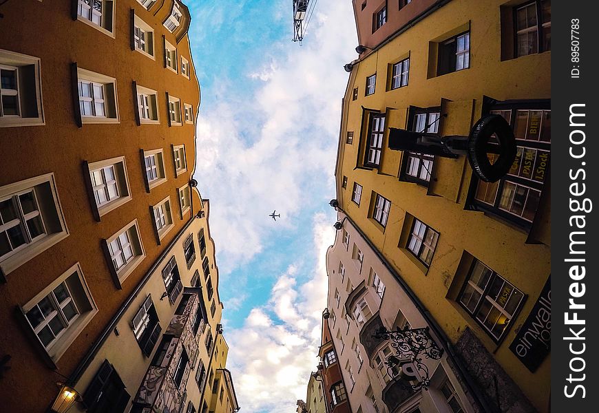 Airplane flying high over facade of modern townhouse buildings on sunny day in blue skies. Airplane flying high over facade of modern townhouse buildings on sunny day in blue skies.