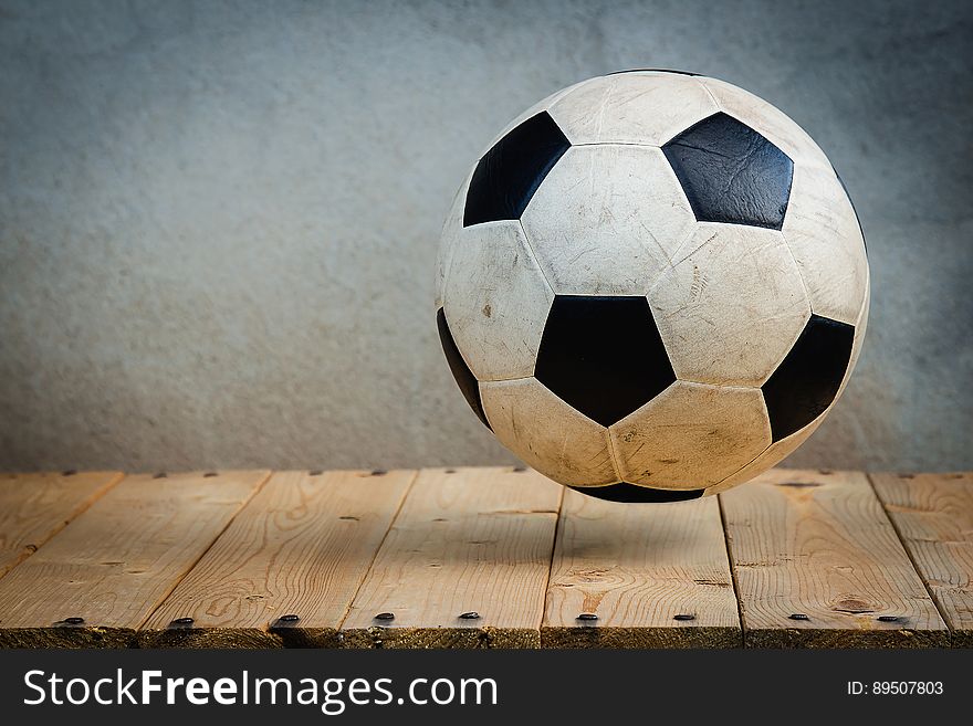 Black and white soccer ball hovering over rustic wooden boards with copy space. Black and white soccer ball hovering over rustic wooden boards with copy space.