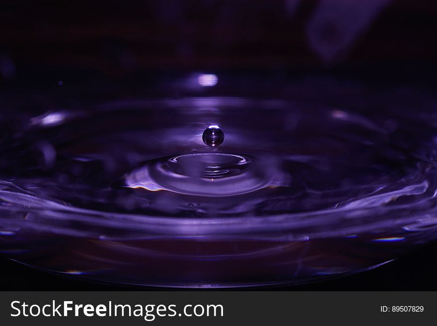 Water drop splashing with ripples in purple liquid. Water drop splashing with ripples in purple liquid.