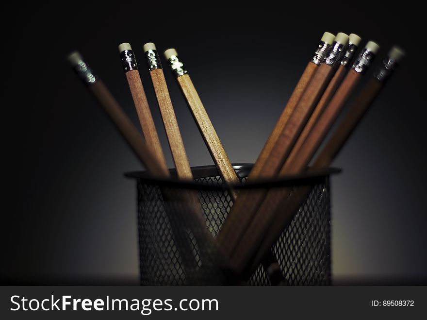 A close up of wooden pencils in a black metal pencil holder. A close up of wooden pencils in a black metal pencil holder.