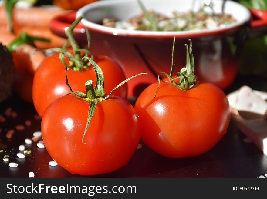 A table with food and three red tomatoes.