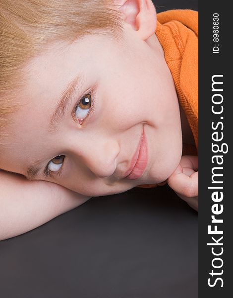 Friendly boy with an orange shirt against a black background