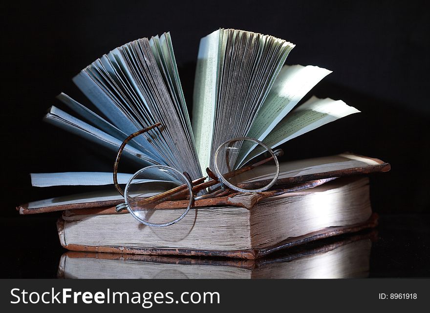 Two antique books with reverberation lying on dark background. Two antique books with reverberation lying on dark background