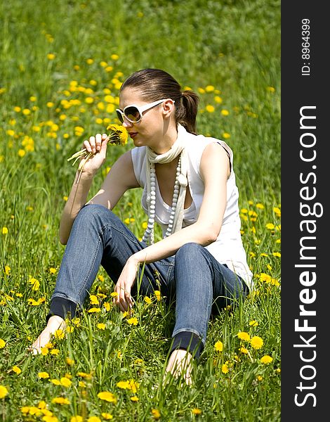 Beautiful young woman with sunglasses in nature smelling a flower. Beautiful young woman with sunglasses in nature smelling a flower