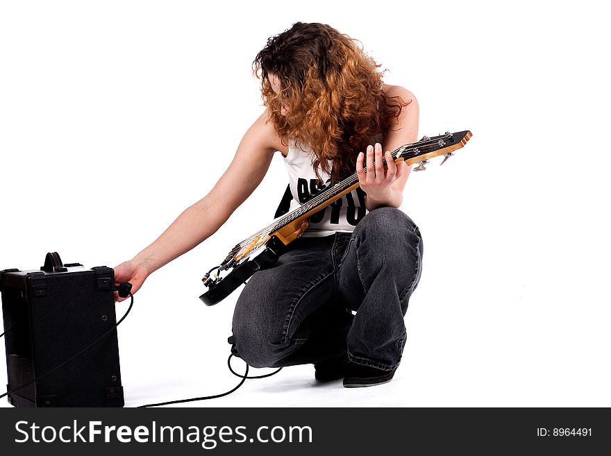 Young girl adjusting her guitar and amplifier. Young girl adjusting her guitar and amplifier