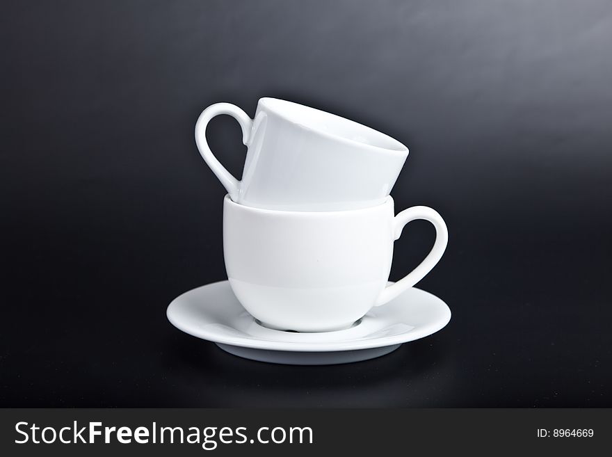 Two cups of white on a black background. Two cups of white on a black background