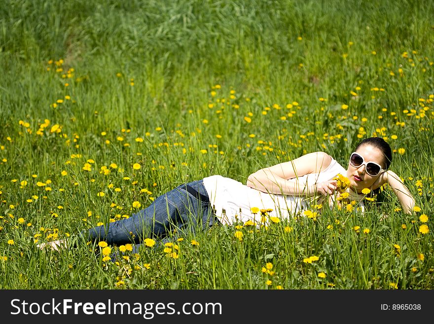 Beautiful young woman with sunglasses in nature smelling flowers. Beautiful young woman with sunglasses in nature smelling flowers
