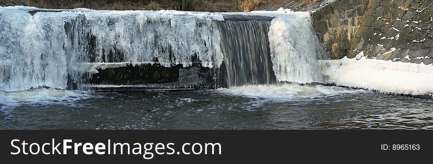 Flowing water in a brook is covered by clear ice. Flowing water in a brook is covered by clear ice