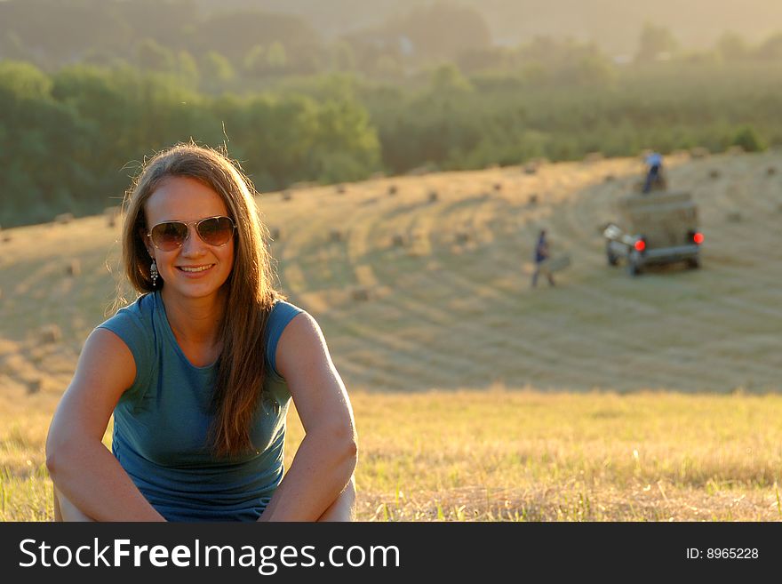 Teenage girl sitting outdoors in a hayfield.