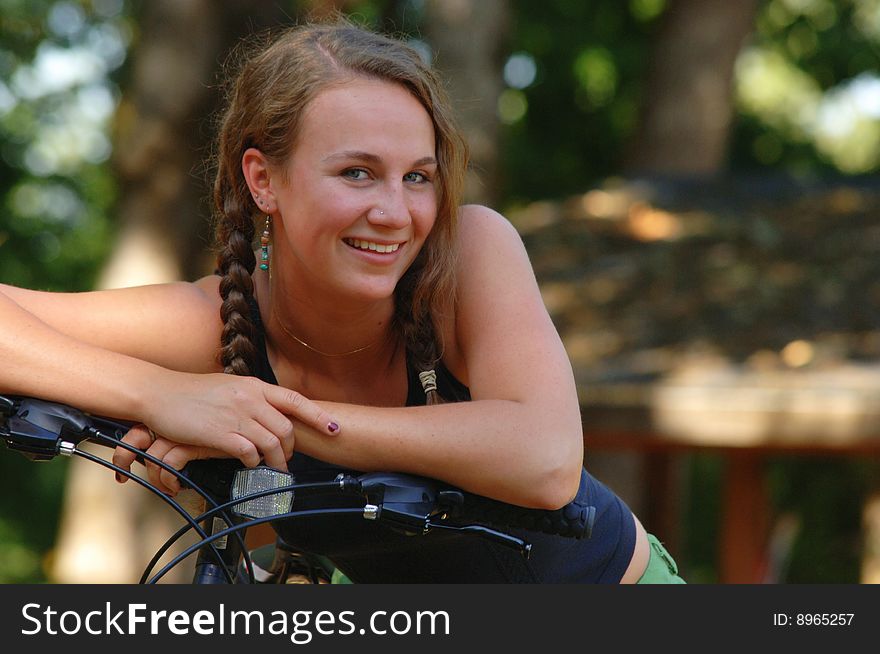 Portrait of a teenage girl resting on handlebars of a bicycle. Portrait of a teenage girl resting on handlebars of a bicycle.