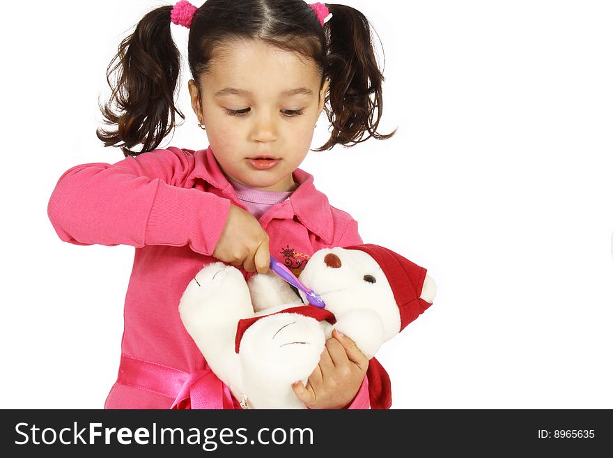 A little girl play brushing the teeth with a teddy bear isolated on white background