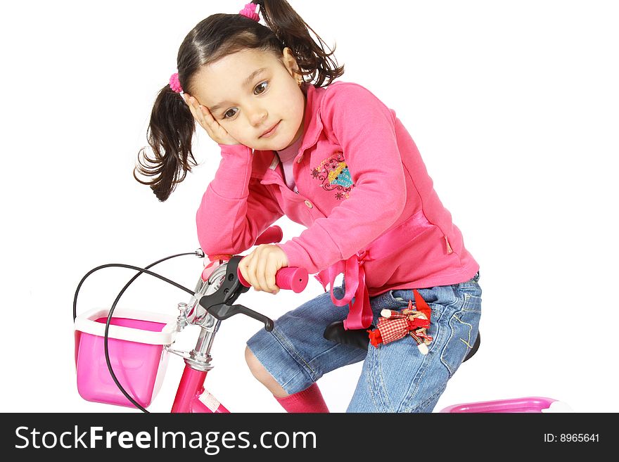 A little girl on a bike with a cogitative look isolated on white background
