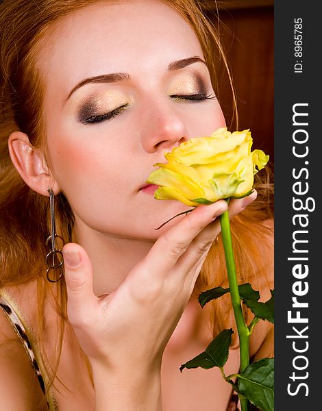 Lovely young woman with yellow rose indoors