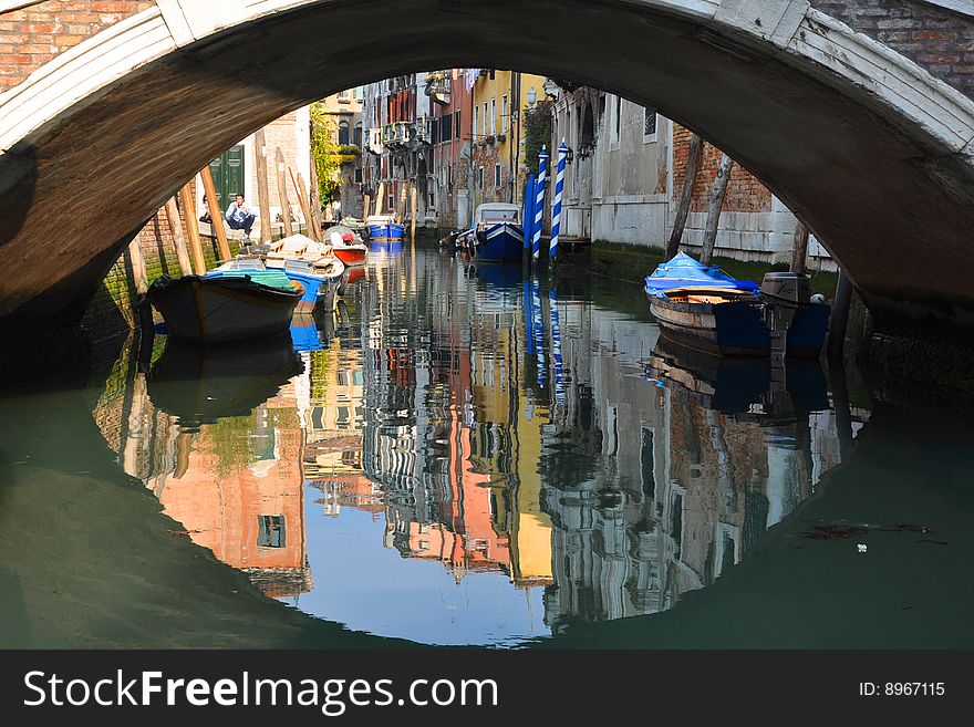 The colored house of venice reflex in the canal under the bridge
