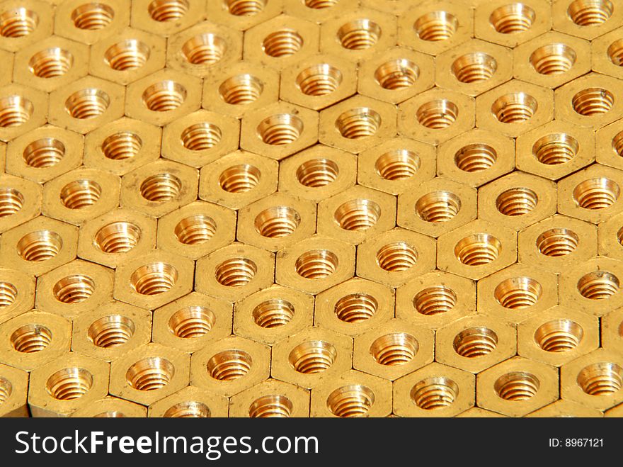 Background made of golden hexadonal screw-nuts. Background made of golden hexadonal screw-nuts