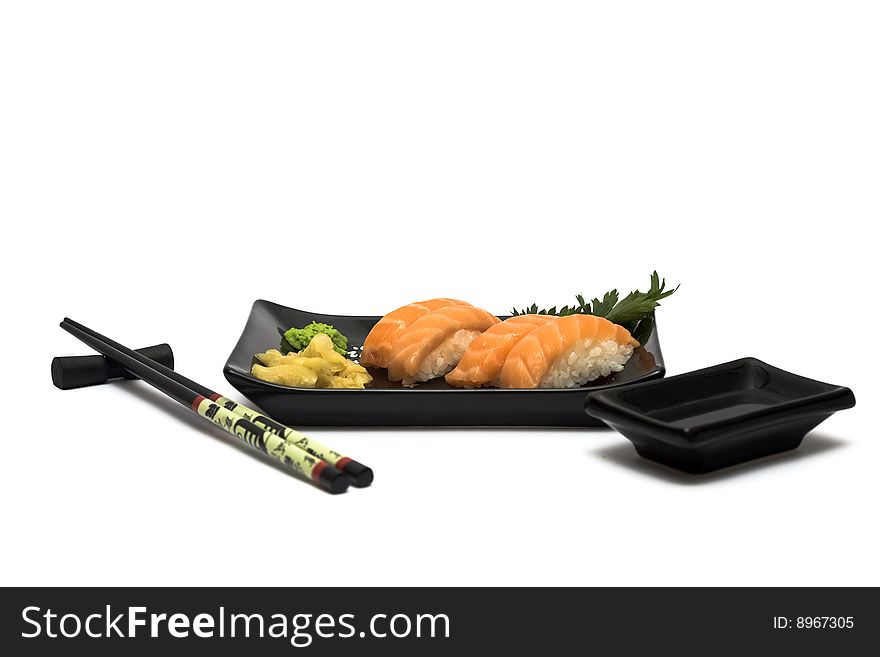 A set of sushi on a black plate with wasabi and gari, isolated on a white background, wish hashi ans soy sauce. A set of sushi on a black plate with wasabi and gari, isolated on a white background, wish hashi ans soy sauce.