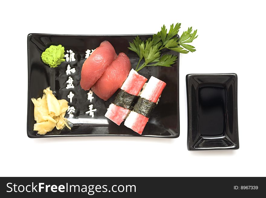 A set of sushi on a black plate with wasabi and gari, isolated on a white background. A set of sushi on a black plate with wasabi and gari, isolated on a white background.