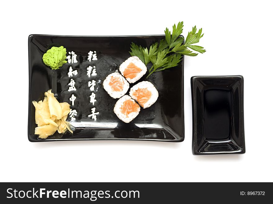 A set of sushi on a black plate with wasabi and gari, isolated on a white background. A set of sushi on a black plate with wasabi and gari, isolated on a white background.