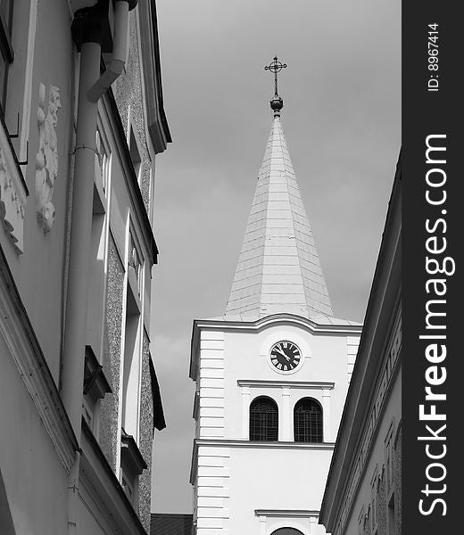 Catholic church tower with clock, view through lane