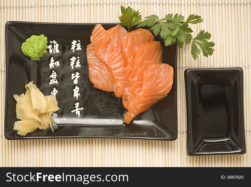 A set of sushi on a black plate with wasabi and gari, on a makisu (bamboo rolling mat). A set of sushi on a black plate with wasabi and gari, on a makisu (bamboo rolling mat).