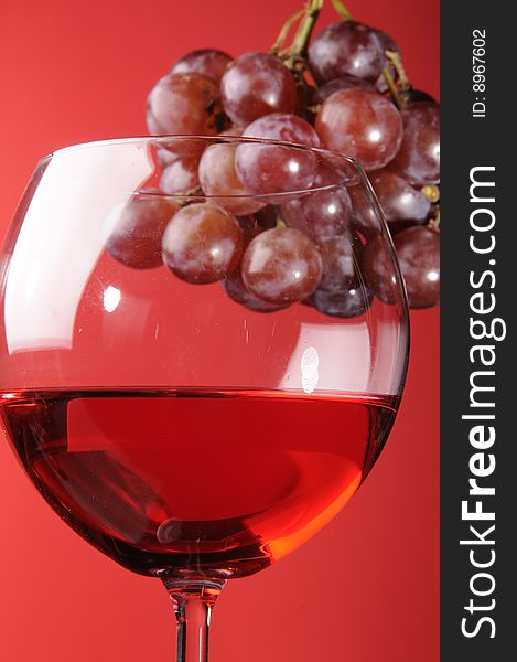 A glass of red wine with red grapes. A glass of red wine with red grapes