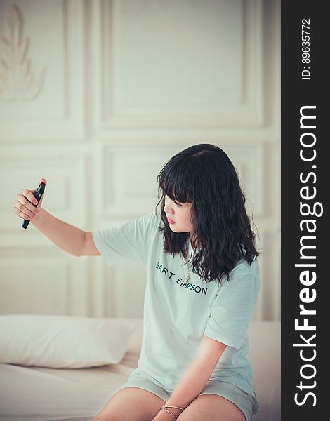 Girl in Blue Crew Neck Shirt Using Her Mobile Phone Indoors