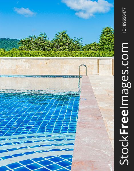 Swimming pool with bright blue tiles outdoors, green countryside and cloudscape background. Swimming pool with bright blue tiles outdoors, green countryside and cloudscape background.