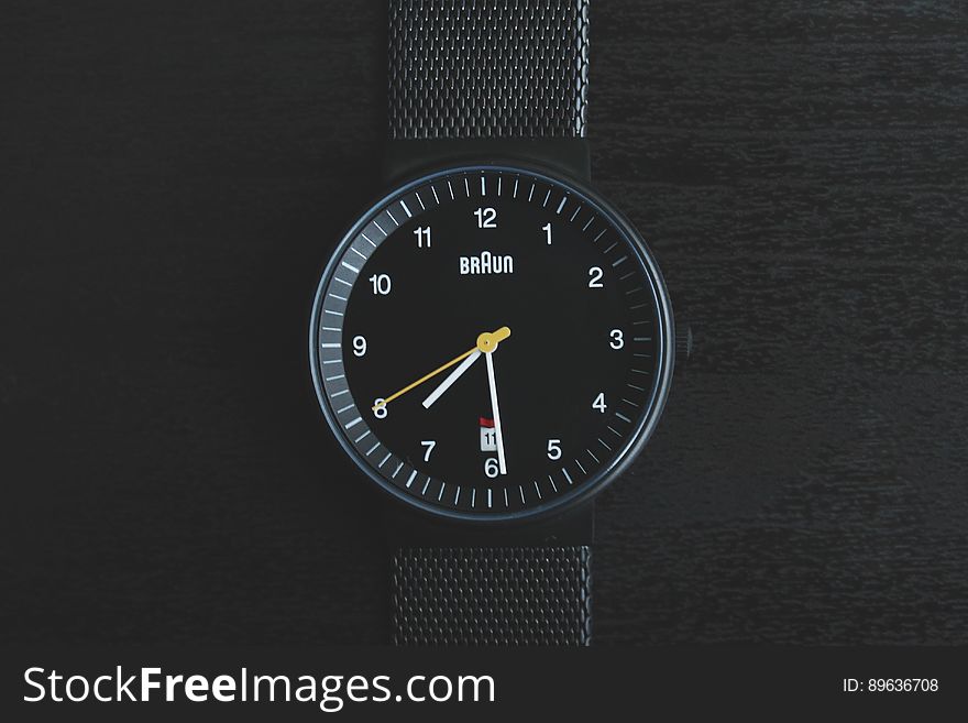 A close up of a simple analog watch on a black background.