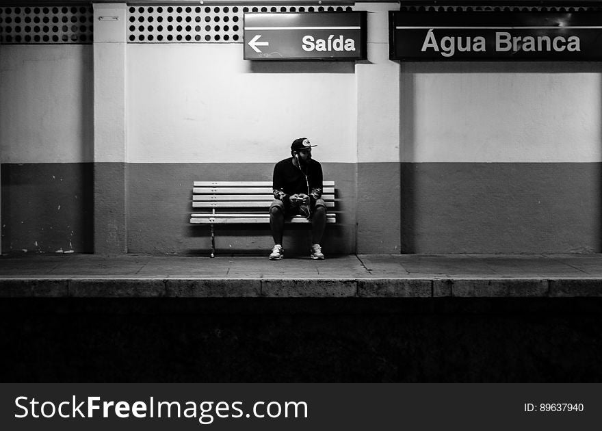 Portrait of man sitting on bench on empty train platform in black and white. Portrait of man sitting on bench on empty train platform in black and white.