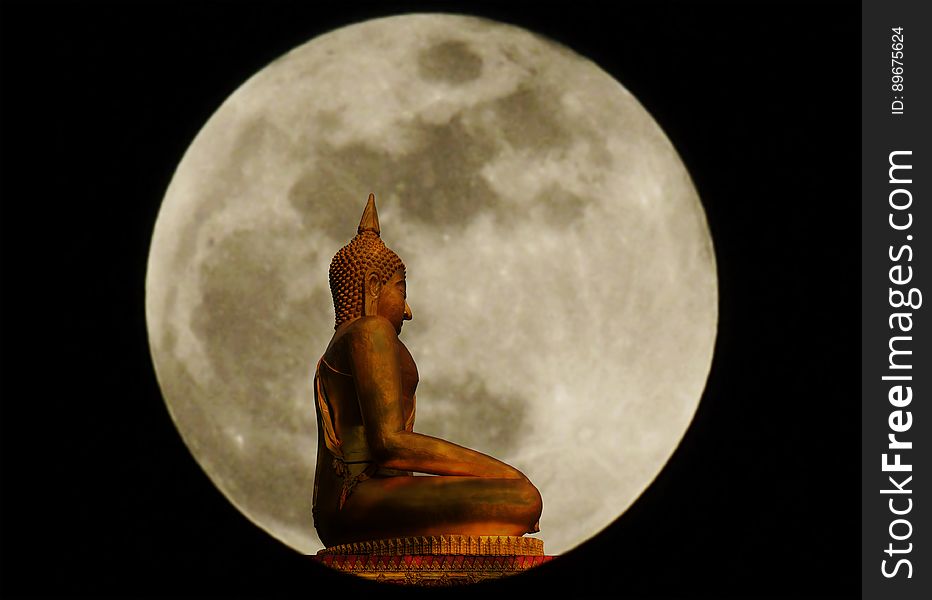 Buddha statue on blurry of full moon background.