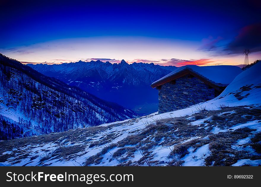 Sunset over alpine cabin on hillside covered in snow, Italy. Sunset over alpine cabin on hillside covered in snow, Italy.
