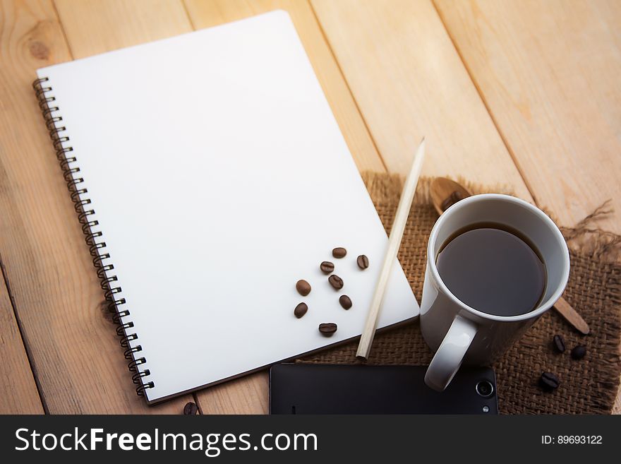 A white notepad with a cup of coffee on the side. A white notepad with a cup of coffee on the side.