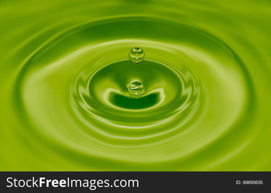 Water drop with ripples on green.