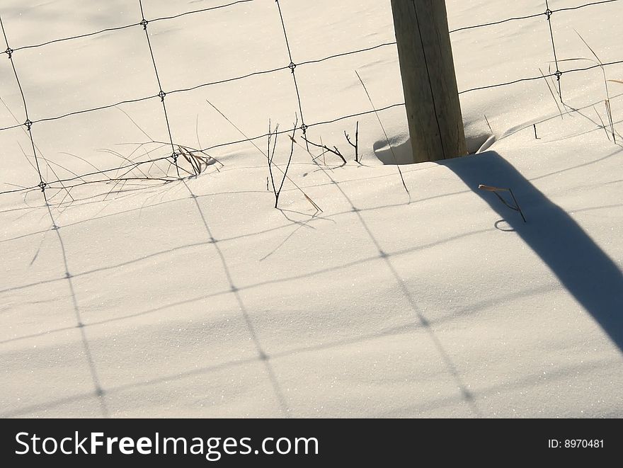 Shadow of fence and post cast on fresh pure snow. Shadow of fence and post cast on fresh pure snow