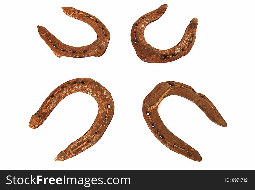 Four old rusty horseshoes on a white