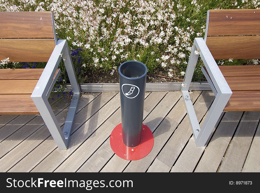 Ashtray in a public place with wooden benches and metal