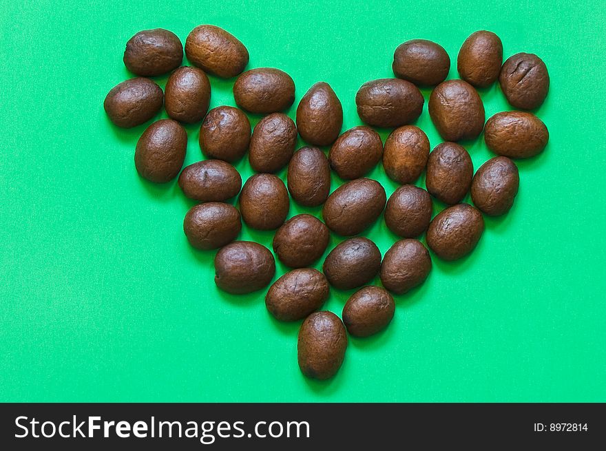 Heart made by coffee beans on green background. Heart made by coffee beans on green background