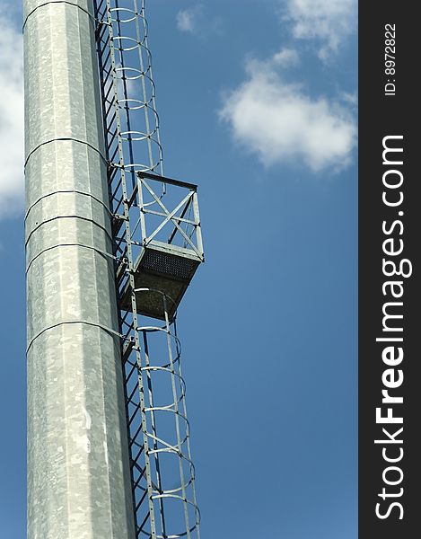 Ladder to the reflector on massive metallic pillar for the stadium lighting. Ladder to the reflector on massive metallic pillar for the stadium lighting