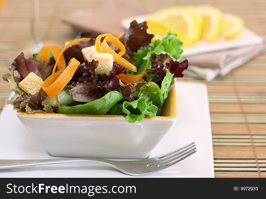 A white bowl of assortment type of lettuce salad