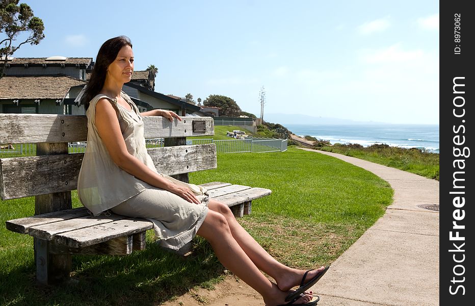 Pretty caucasian girl sitting on the wooden branch over green grass