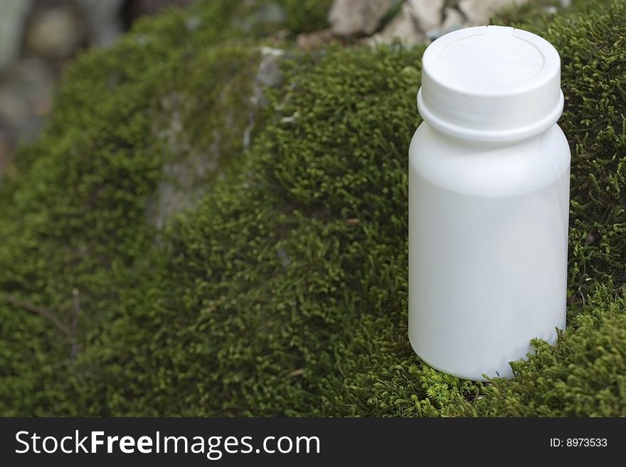 Vitamin, or medication box on a mossy stone. There is a white jar waiting for your logo and the name of your product. Vitamin, or medication box on a mossy stone. There is a white jar waiting for your logo and the name of your product.