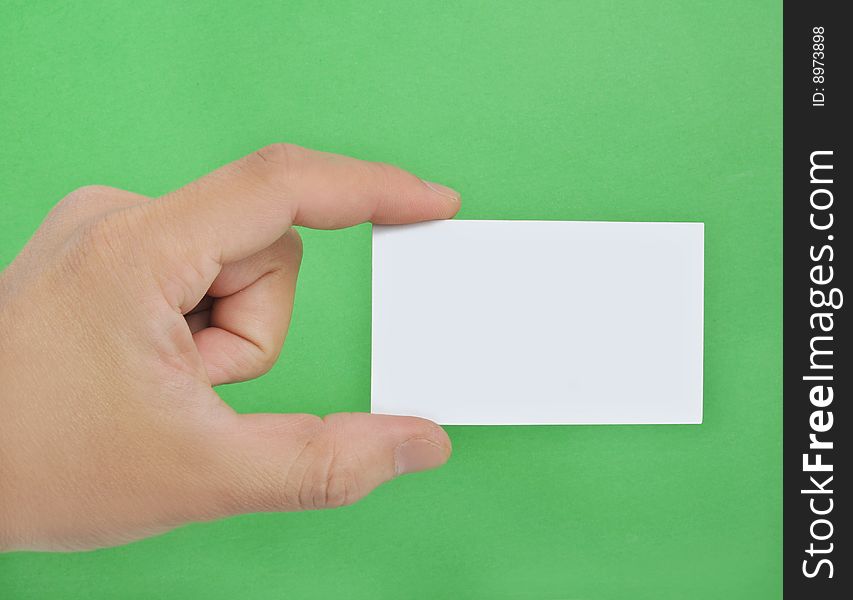 Hand holding a blank business card in the green background