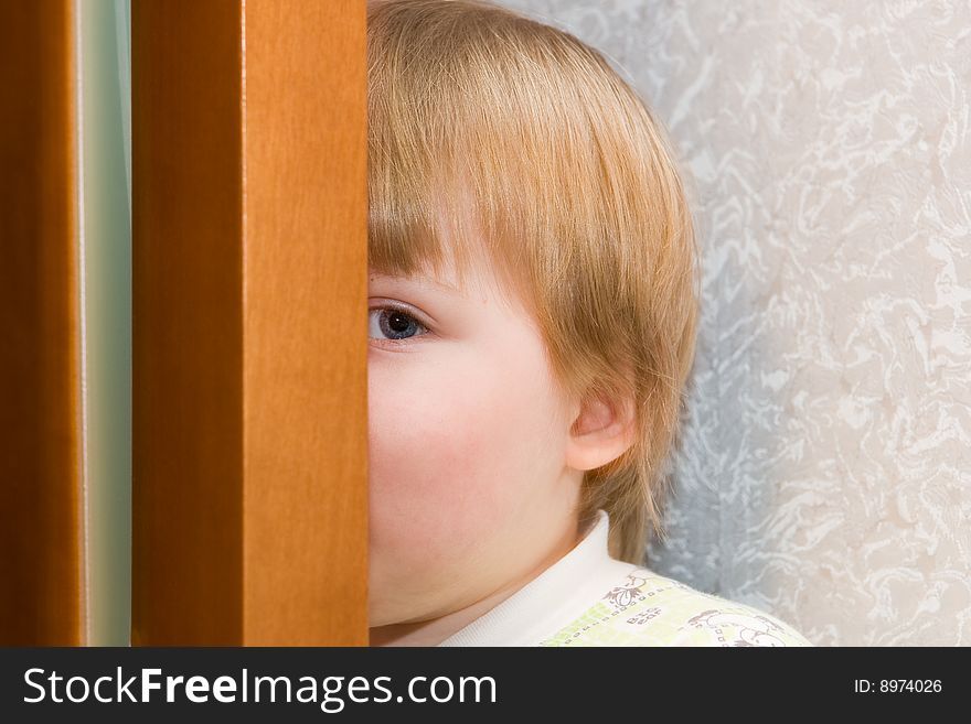 Child hides behind a door