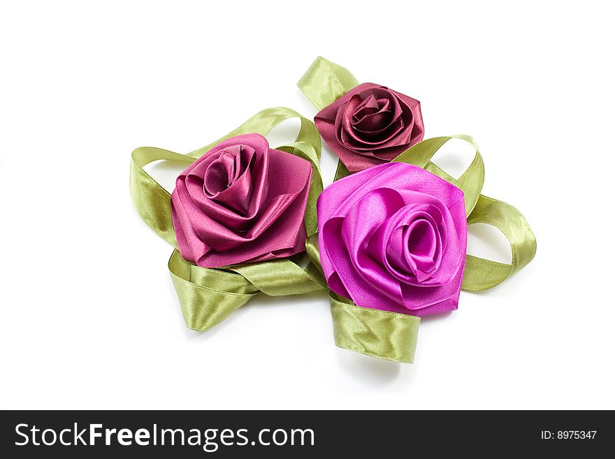 Artificial flowers-roses from satiny tapes on a white background. Artificial flowers-roses from satiny tapes on a white background