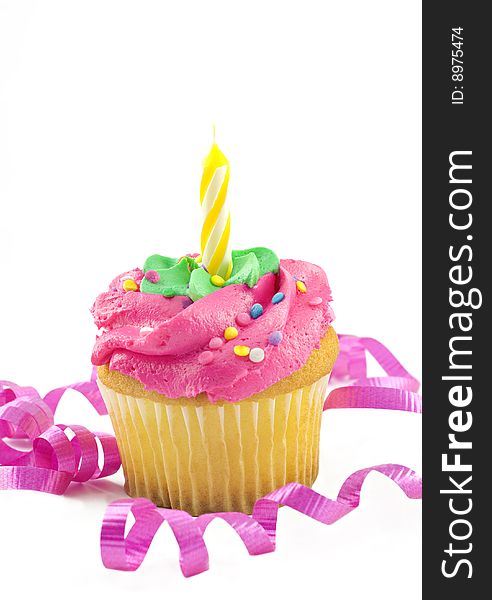 A single pink cupcake with one unlit candle decorated with curly pink ribbon, vertical with white background and copy space. A single pink cupcake with one unlit candle decorated with curly pink ribbon, vertical with white background and copy space