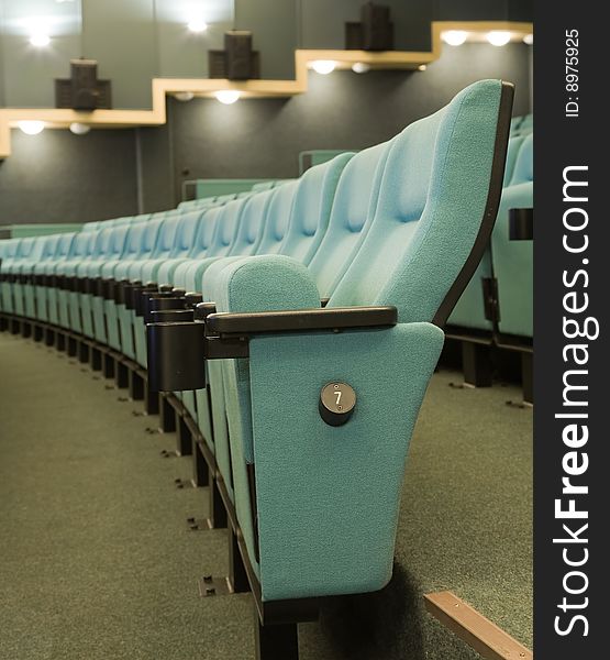 Row number seven. Row of green chairs in auditorium. Row number seven. Row of green chairs in auditorium.