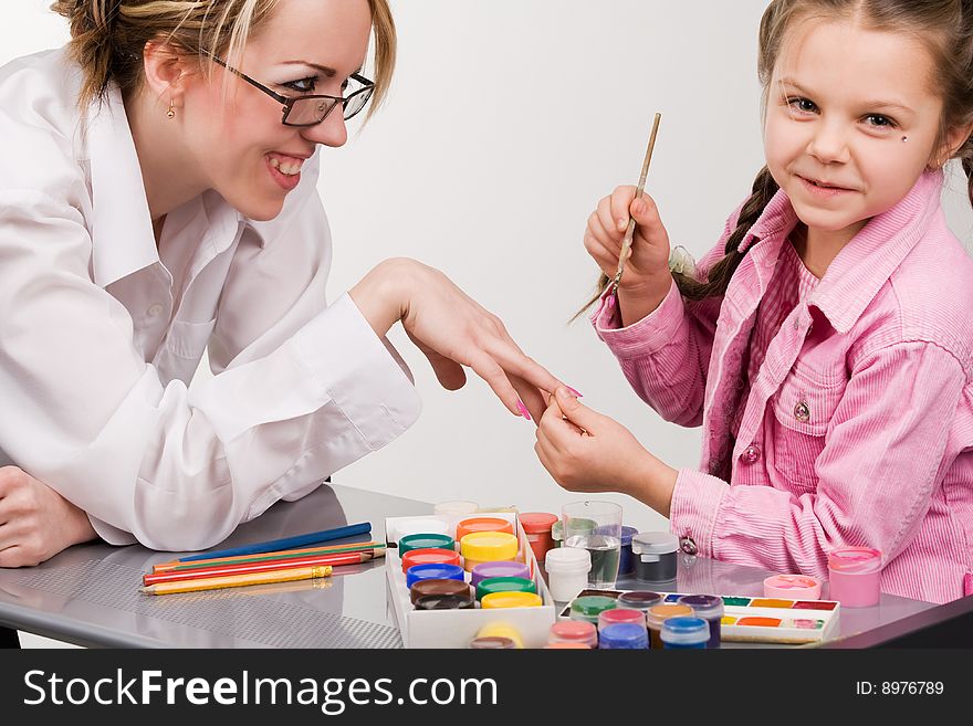 Little girl playing with mom, painting her fingers. Little girl playing with mom, painting her fingers