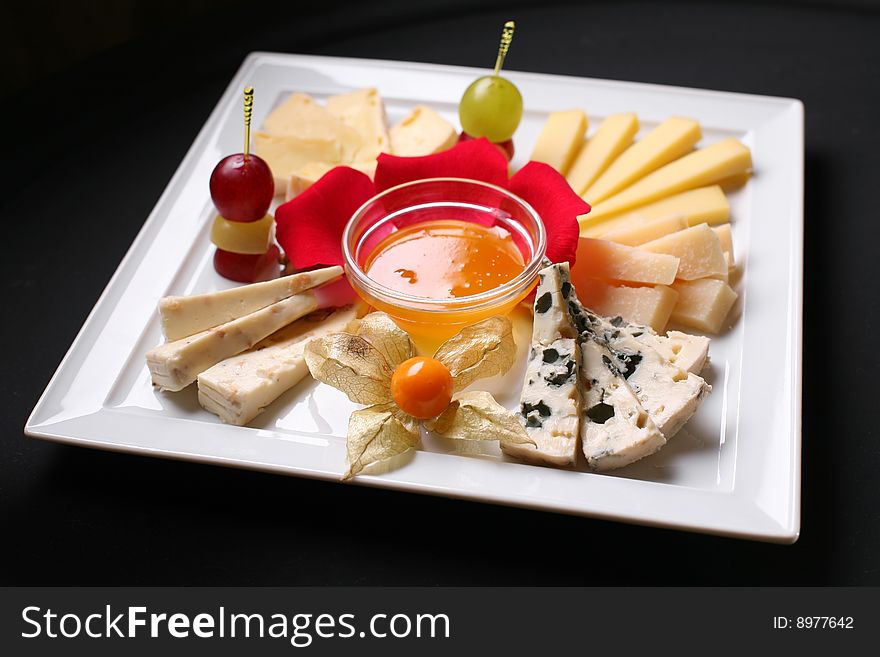 Fruit and cheeses are in ceramic tableware.