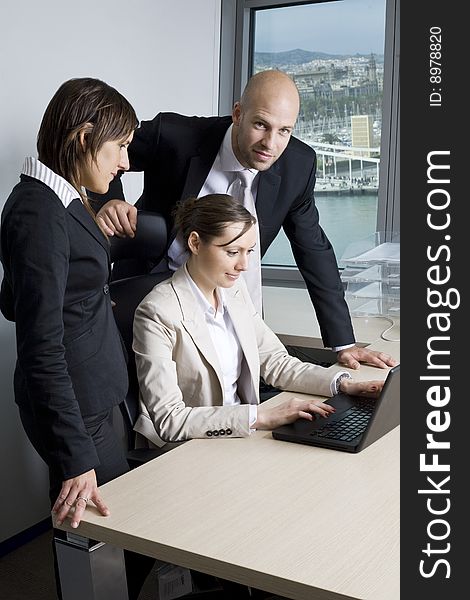 Young businessteam of three persons in office. In the background the skyline of Barcelona/Spain.