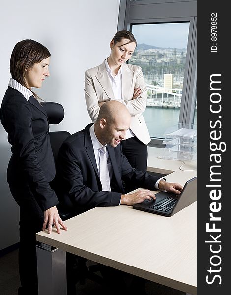 Young businessteam of three persons having fun in office. In the background the skyline of Barcelona/Spain.